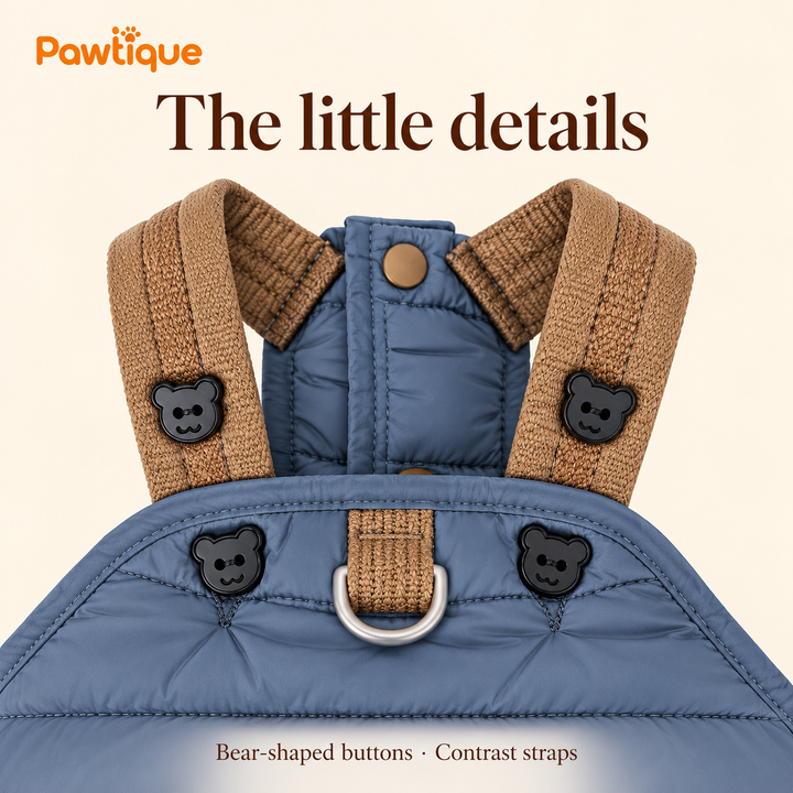 Close-up of bear-shaped buttons, brown shoulder straps and metal D-ring on the blue jumpsuit