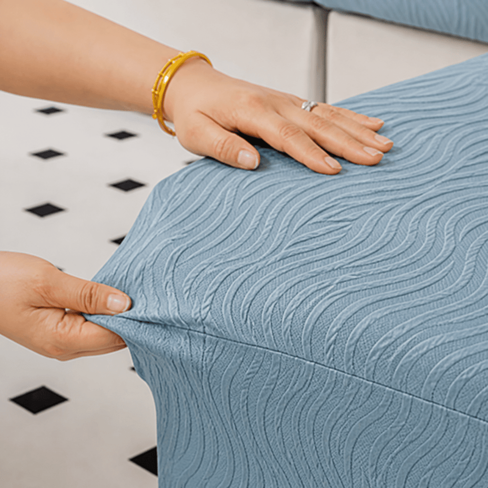 Hands fitting a blue wave-pattern stretch cover around a seat cushion.