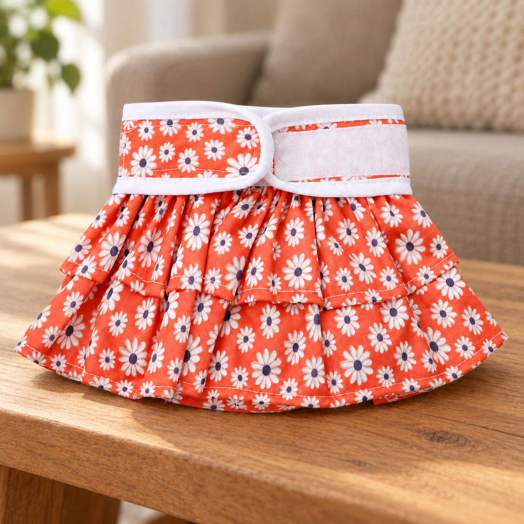 Daisy-print pet diaper pants with ruffled trim on a warm wood surface.