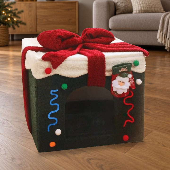 Christmas gift-box covered pet bed with original Santa stocking decoration, green panels and red bow on a warm wooden floor.