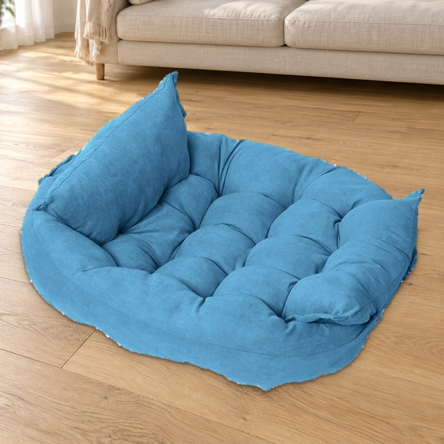 Light Blue foldable quilted pet bed with raised padded sides resting on a wood floor beside a cream sofa