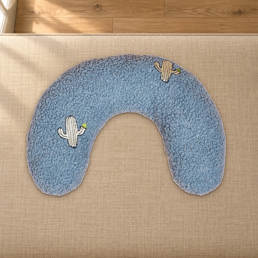 Cactus-patterned blue-gray U-shaped pet pillow resting on a fabric-covered bench