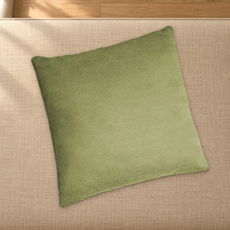 Green herringbone chenille pillow styling reference resting on a fabric-covered bench