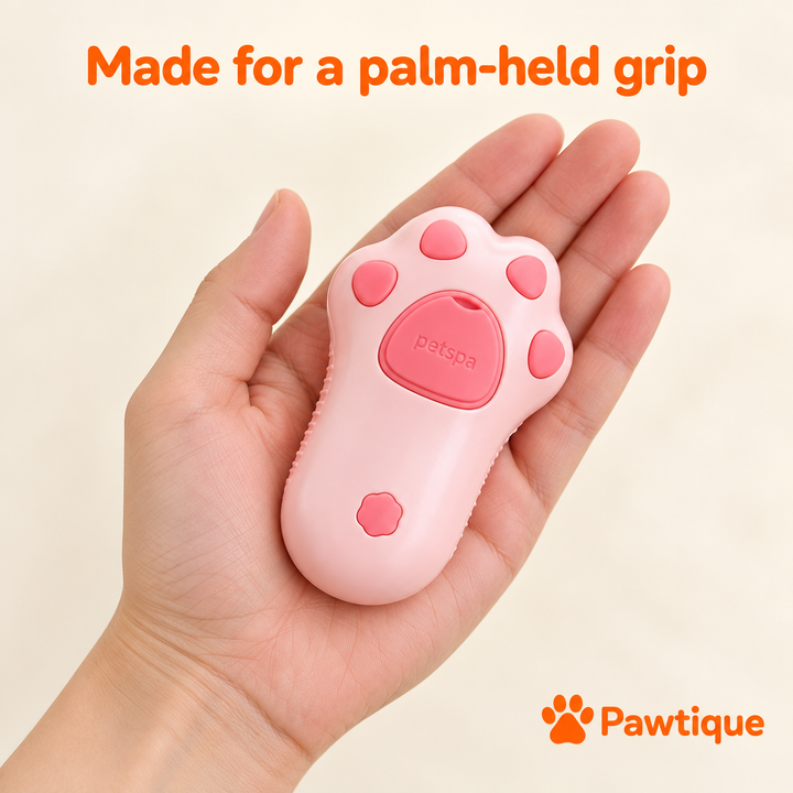 Pink spray grooming brush shown resting in an adult palm.
