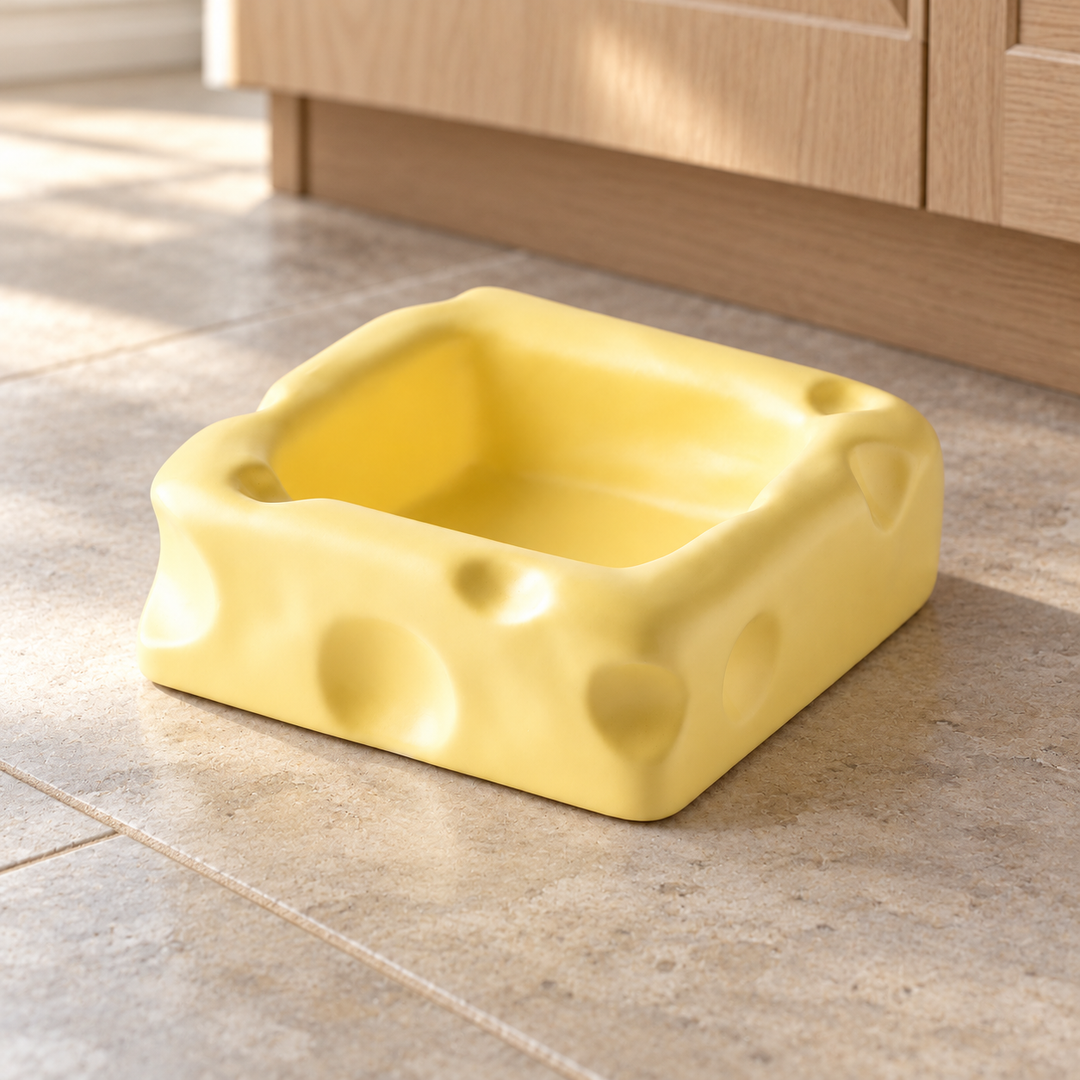 Yellow large square cheese-shaped ceramic pet bowl on a natural stone kitchen floor.