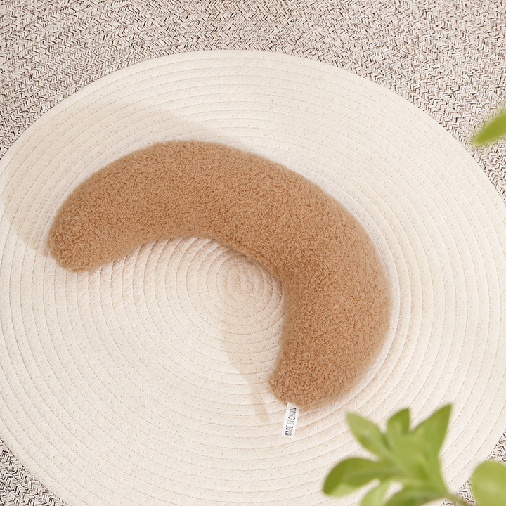 Coffee plain crescent pet pillow on a woven mat