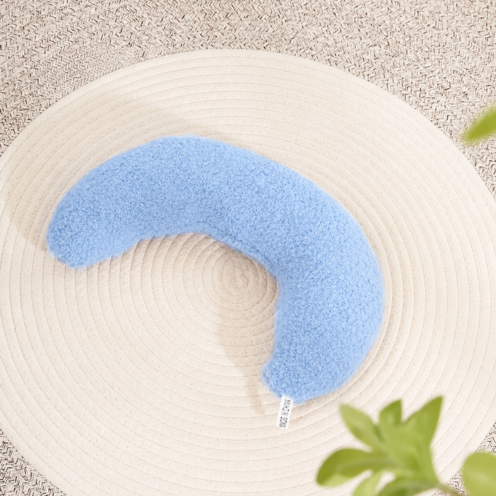 Sky blue plain crescent pet pillow on a woven mat