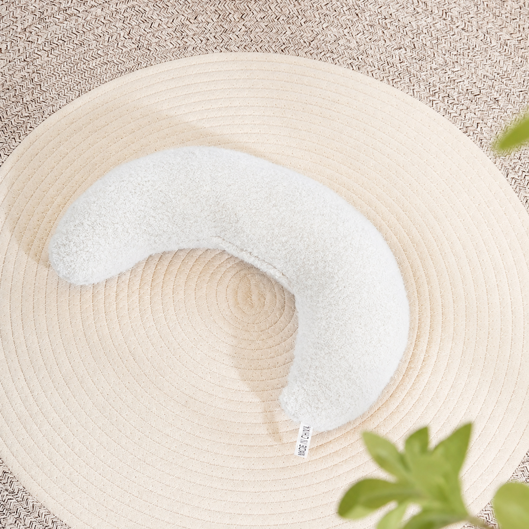 White plain crescent pet pillow on a woven mat