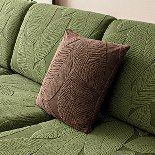 Brown leaf-pattern pillow shown on a green covered sofa; selected pillow option only.