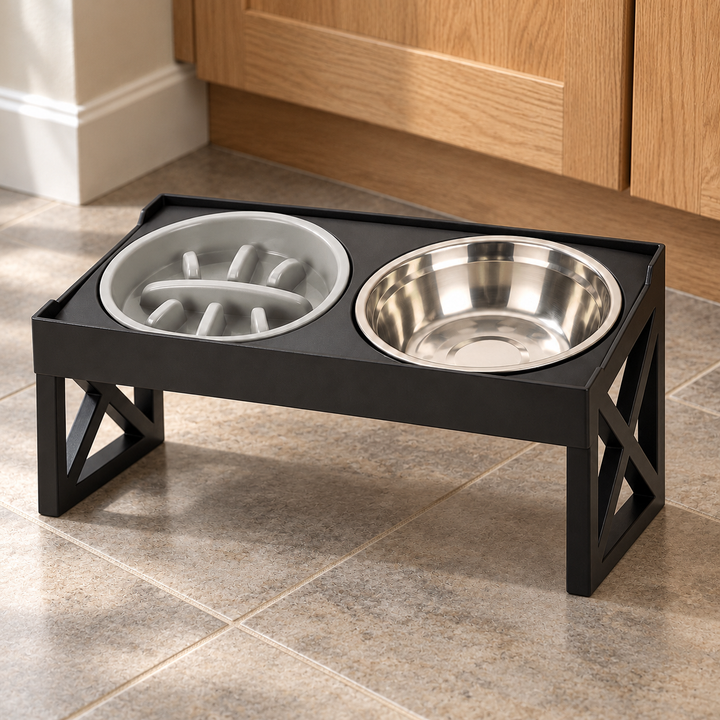 Black elevated stand with a gray slow-feeder bowl on the left and stainless steel bowl on the right, shown on a tiled kitchen floor.