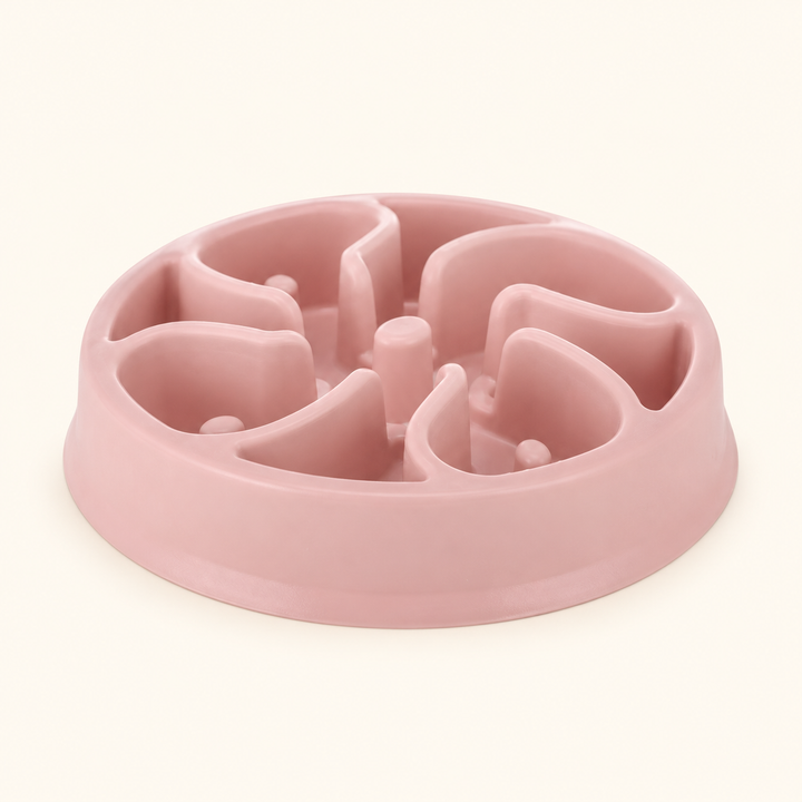 Pink slow-feeder dog bowl with curved ridges and rounded posts on a warm-cream background