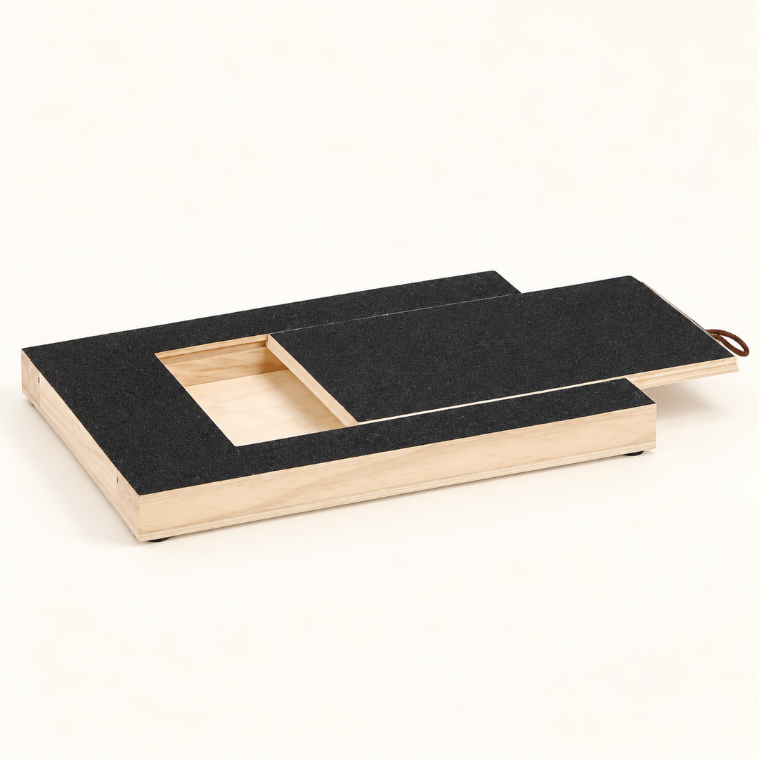 Dog nail scratch board with a black abrasive surface, partly open sliding lid, cord-loop pull and recessed treat compartment.