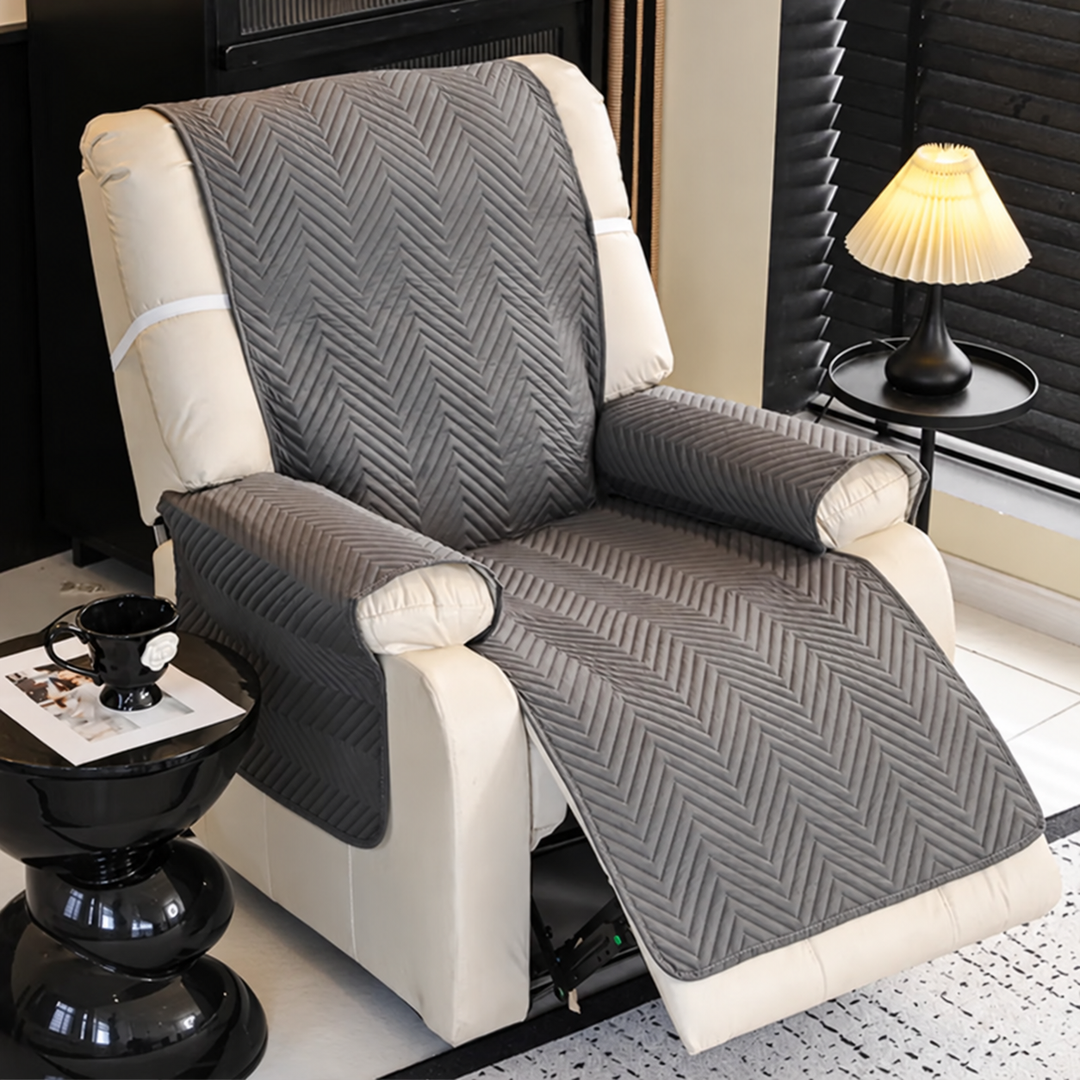 Gray quilted cover draped over an open recliner, with cream upholstery visible at the sides.